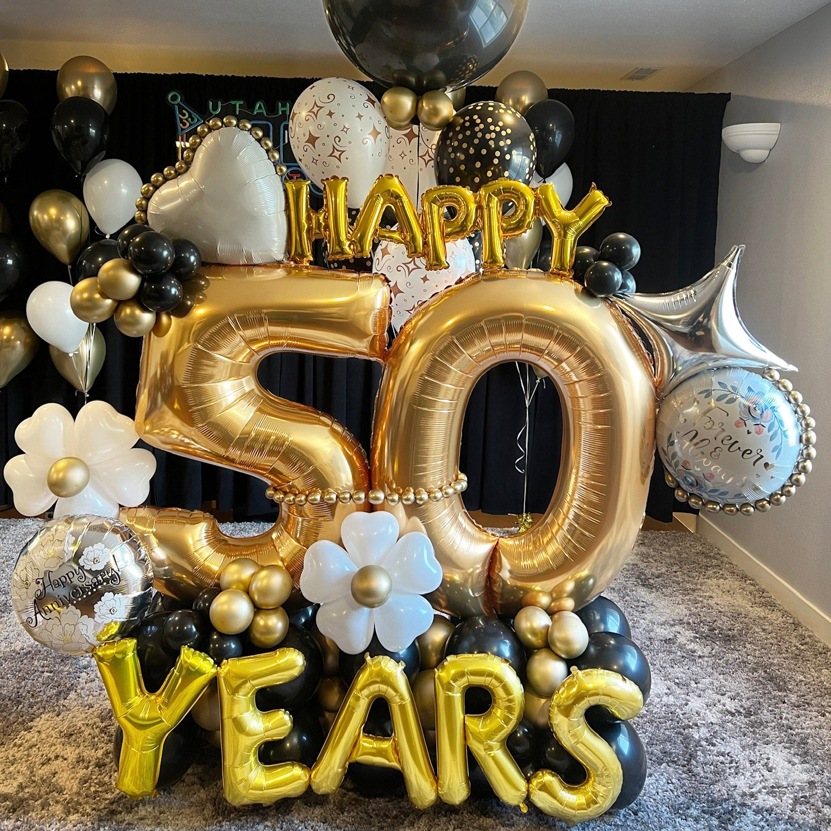 "Happy 50 Years" golden anniversary balloon display with black, gold, and white balloons