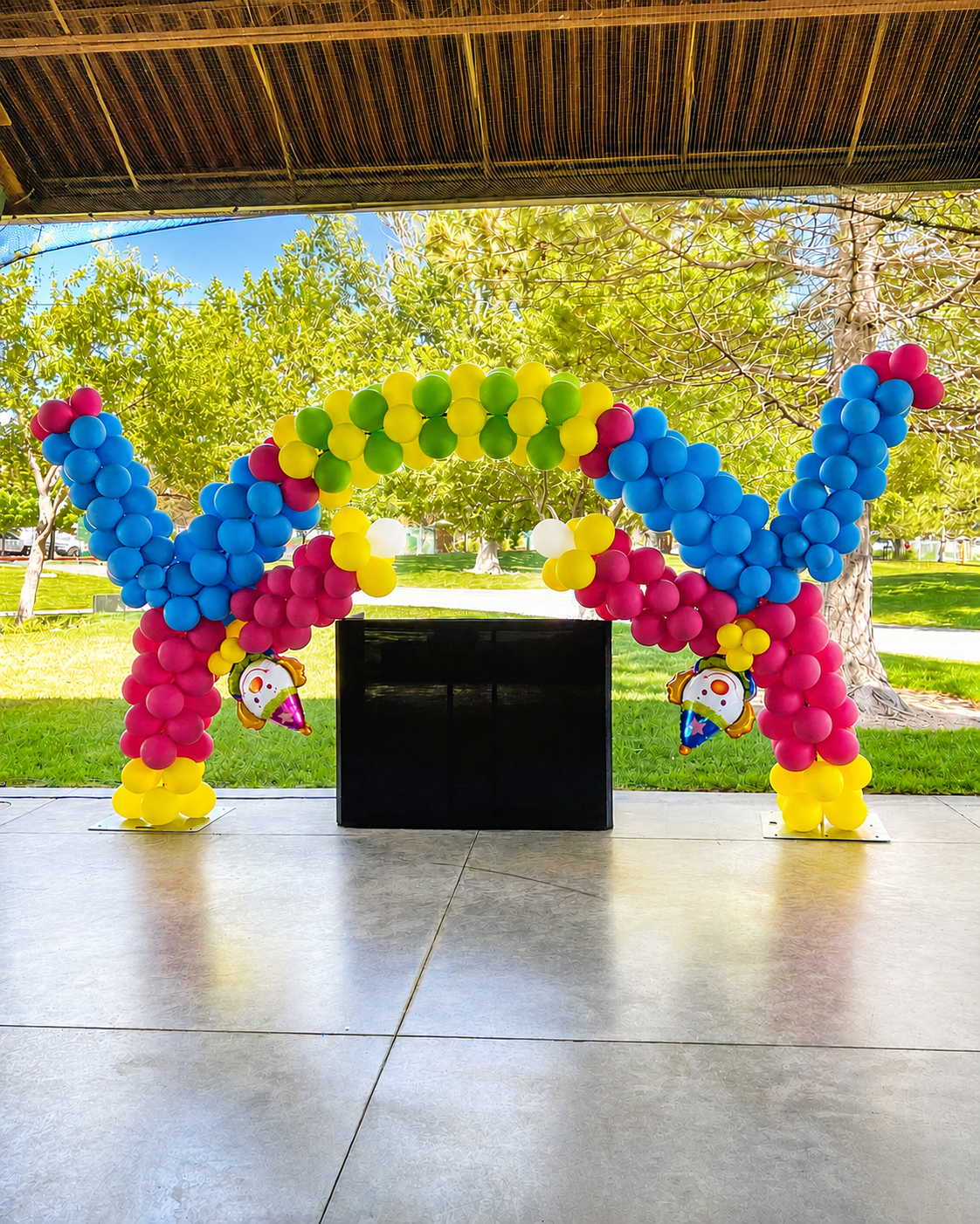 Balloons on a frame create balloon arch depicting 2 clowns doing a cartwheel for back to school, end of summer outdoor party in Lehi, Utah park