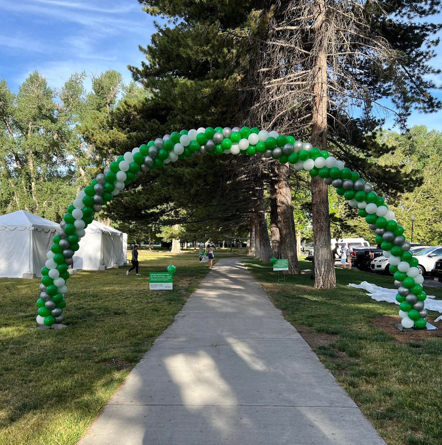 green, white, silver balloon arch over sidewalk for arthritis walk fundraiser