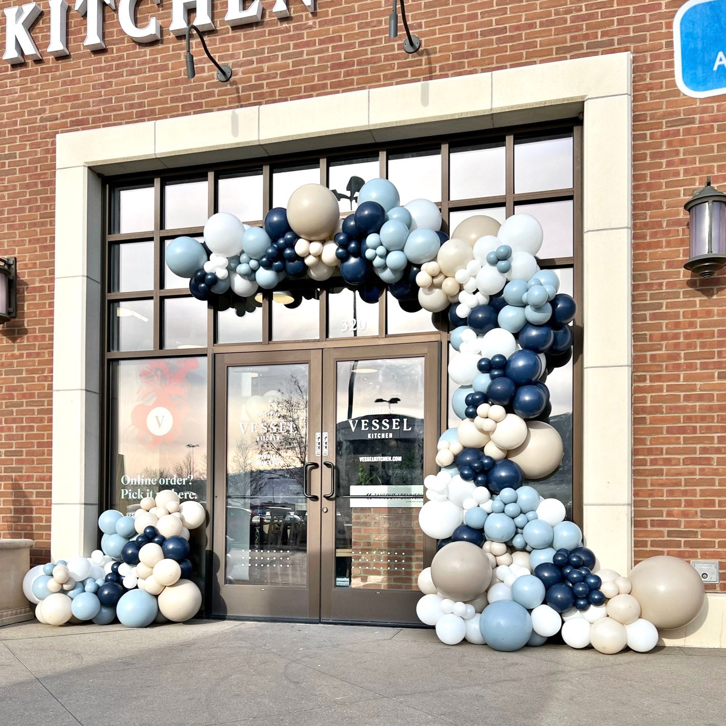 Balloon arch in shades of blue and white sand to mark the grand opening of Vessel Kitchen