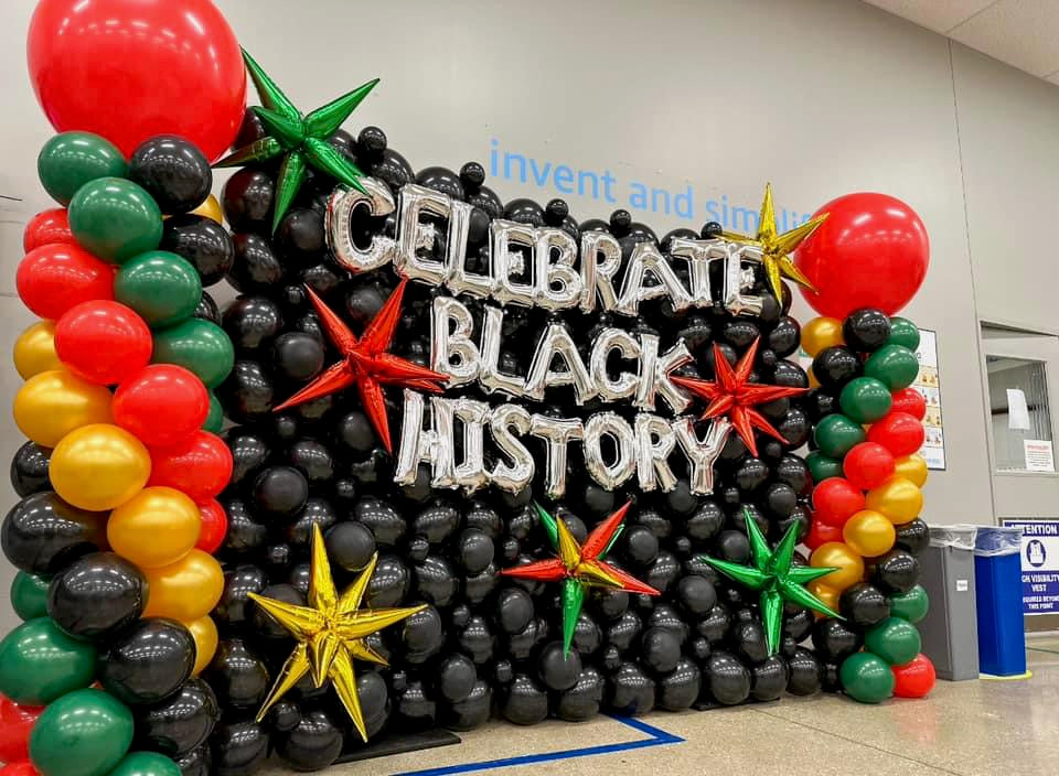 Large balloon wall reads "Celebrate Black History" with classic balloon columns on the side