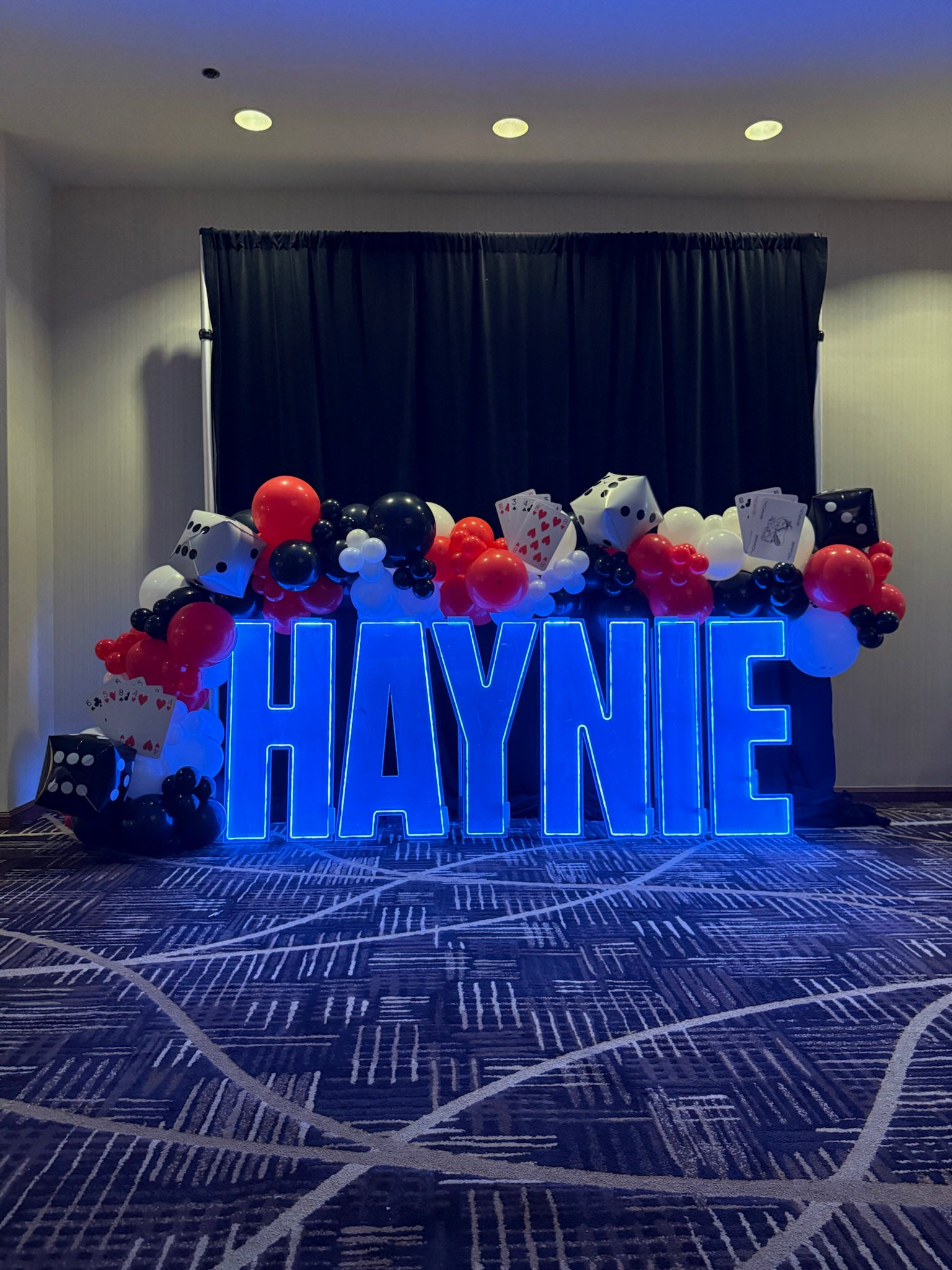 red, black, white casino themed garland drapes across HAYNIE led light up marquee letters