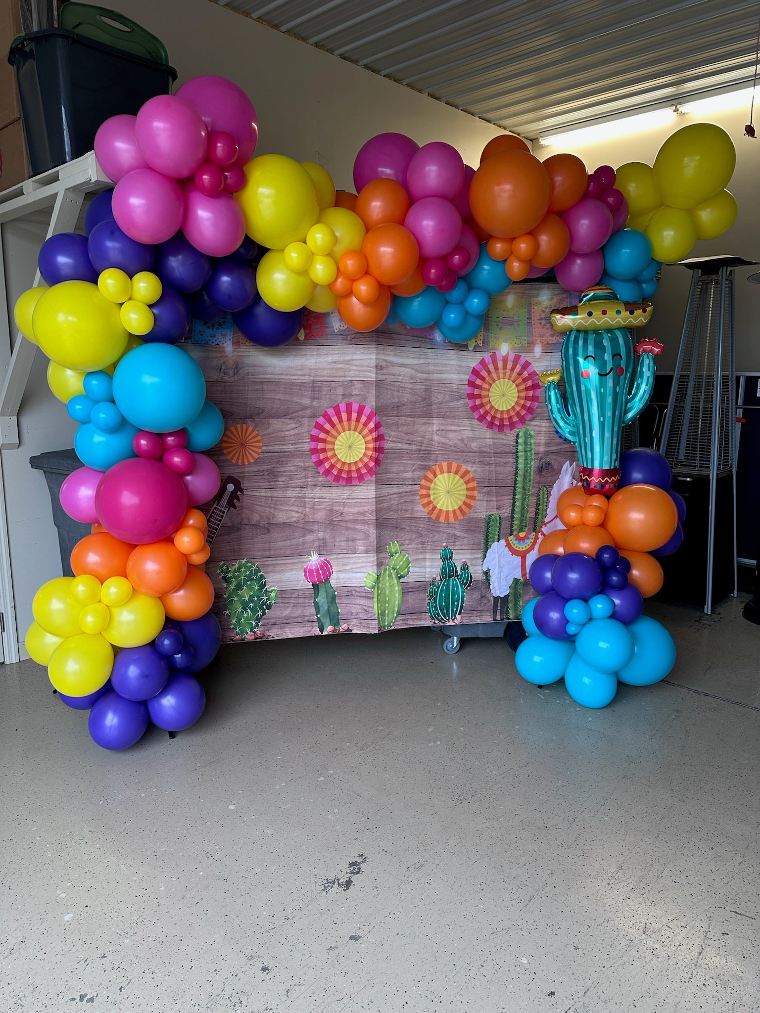 Colorful balloon arch with a cactus and sun design in the background.