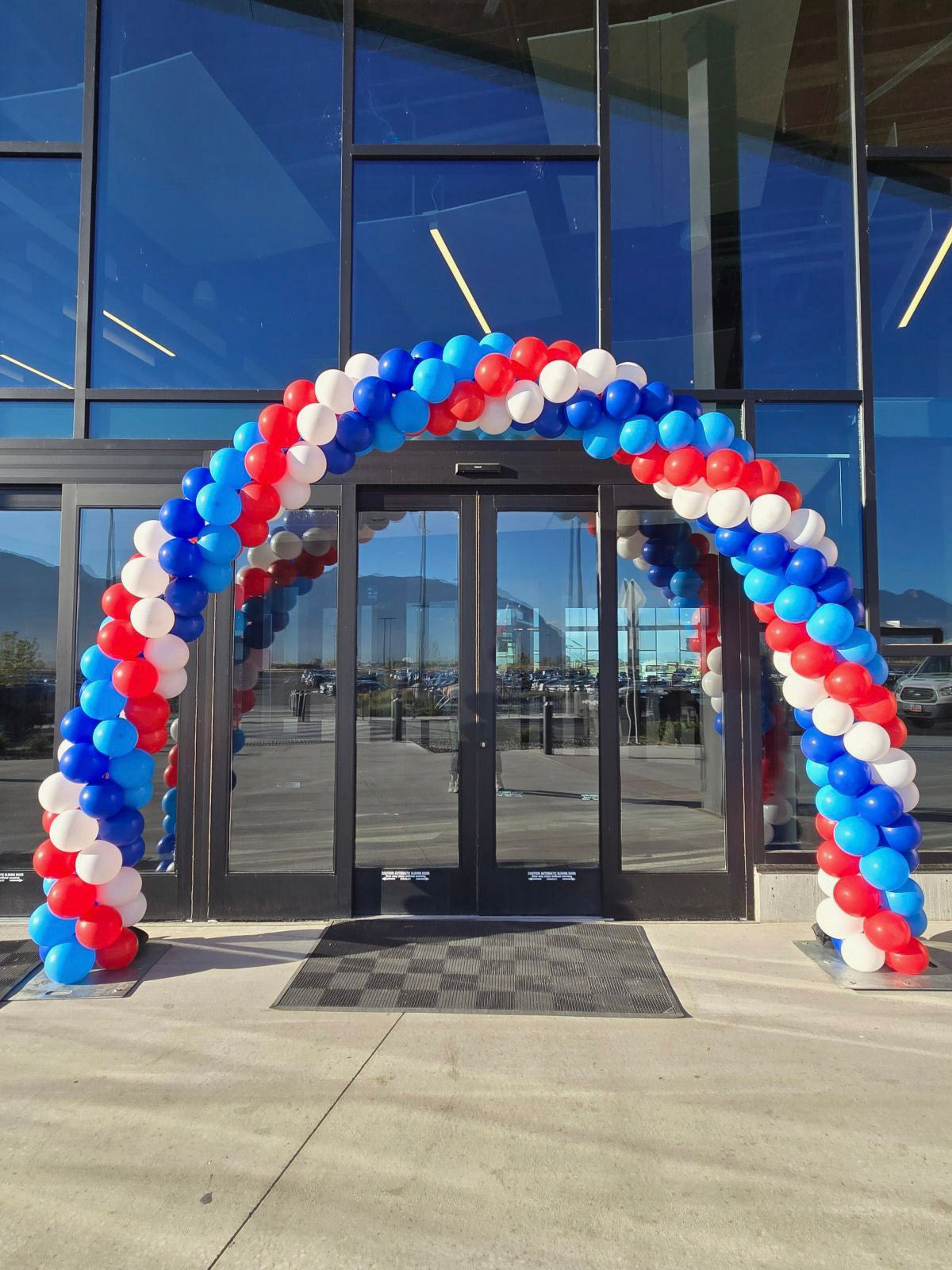 red, white, blue balloons form a classic balloon arch entrance at the front of a building, the Provo City airport