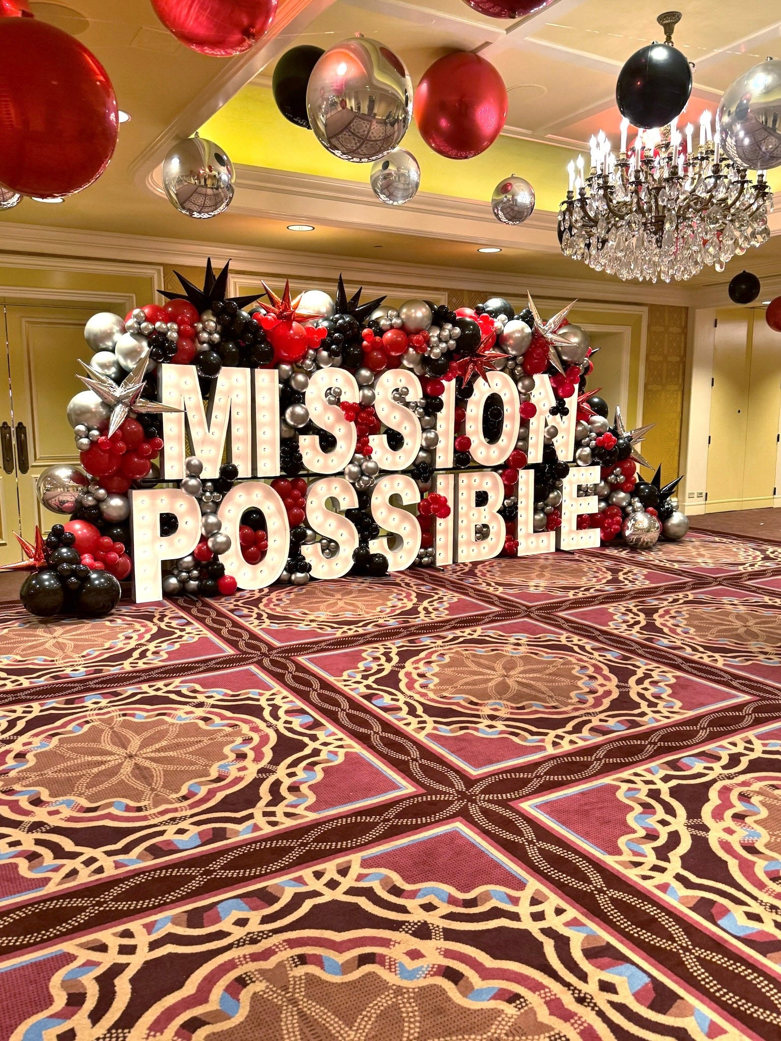 Decorative setup with 'MISSION POSSIBLE' text and balloons in a formal hall.