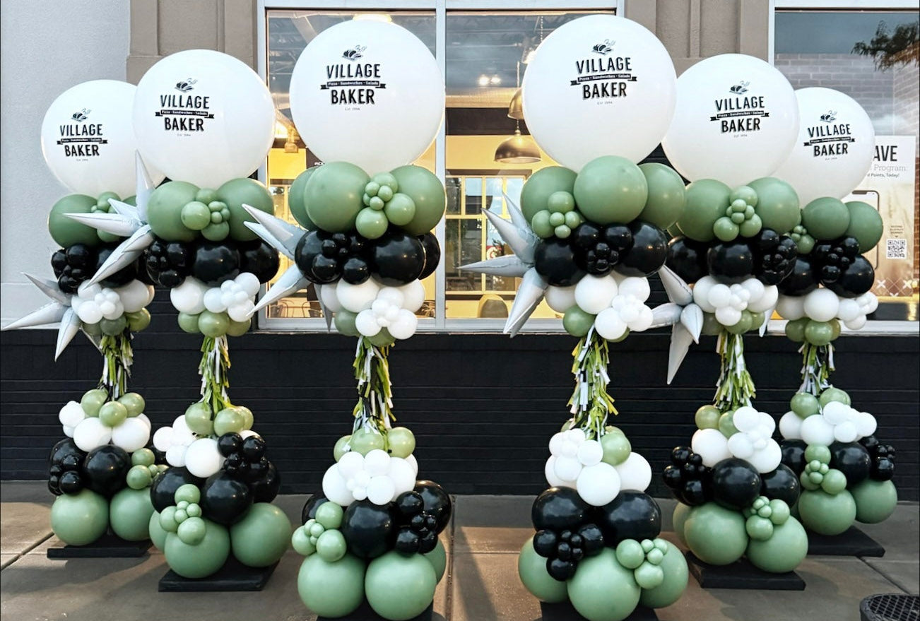 Decorative balloon towers for grand opening with 'Village Baker' branding in front of a building.