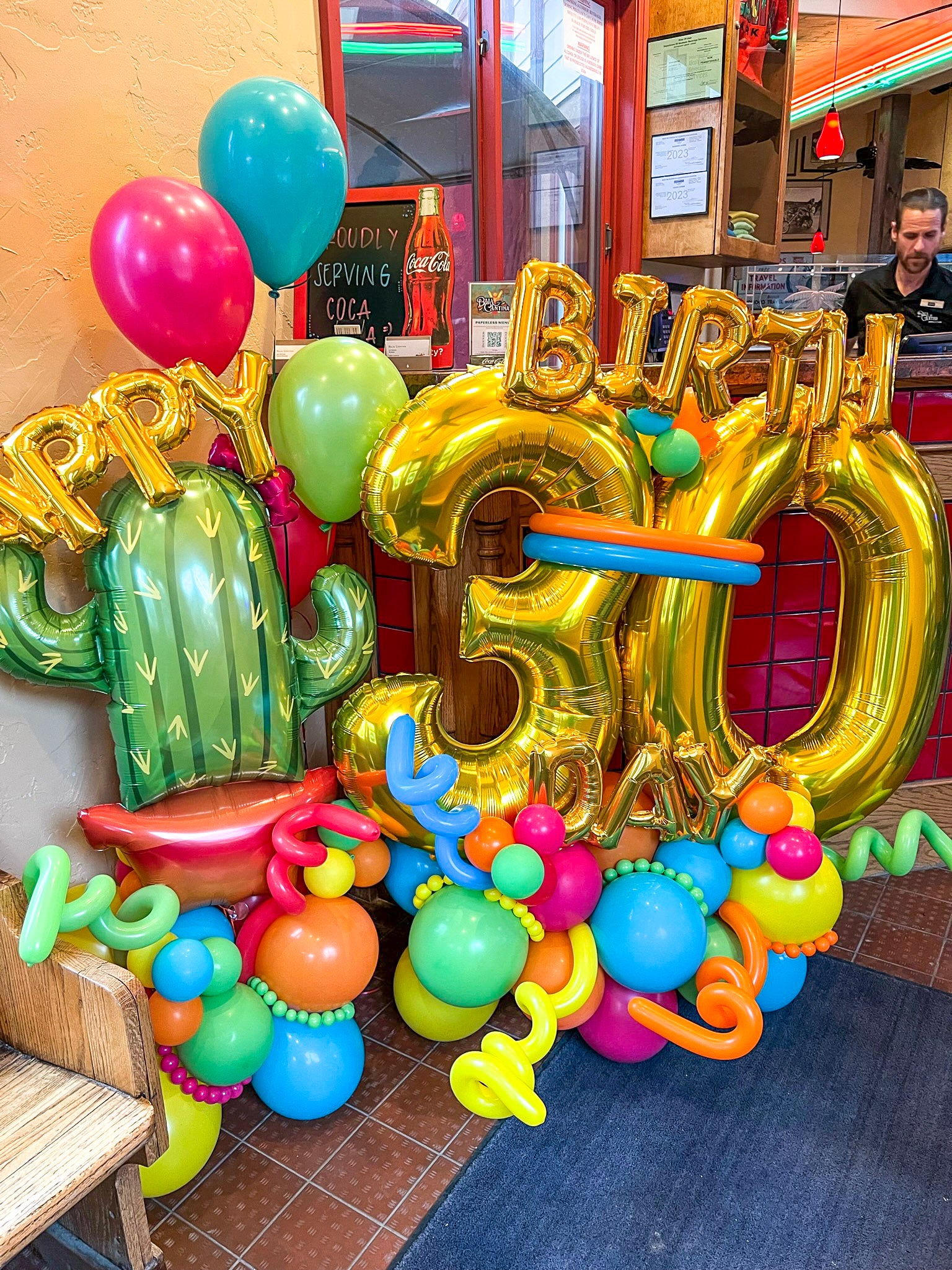 Colorful birthday decorations with balloons and arch in a casual setting.