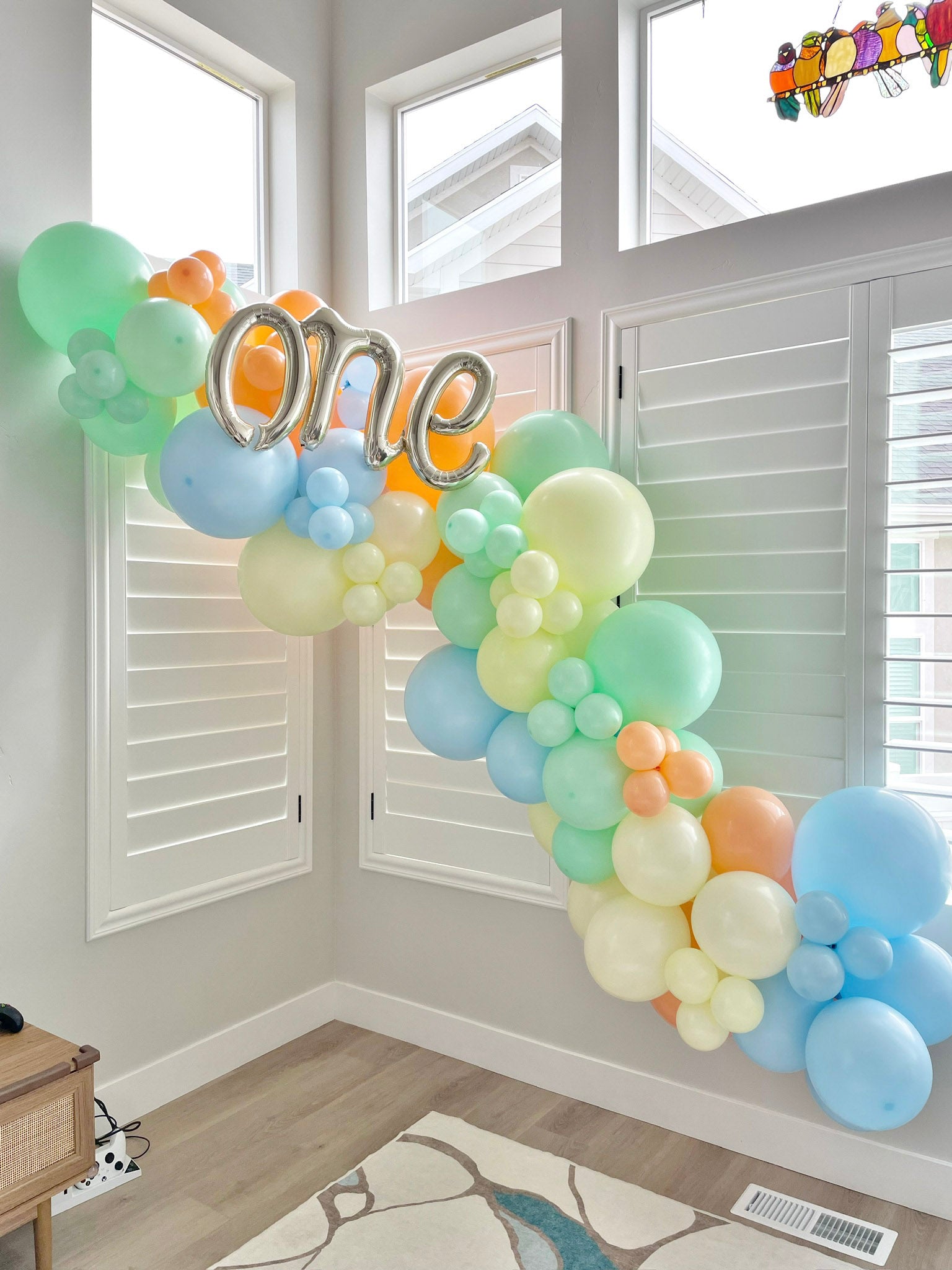 9 foot balloon garland winds up the walls and windows of a Utah county home featuring pastel blue, green, yellow, and cream orange. 