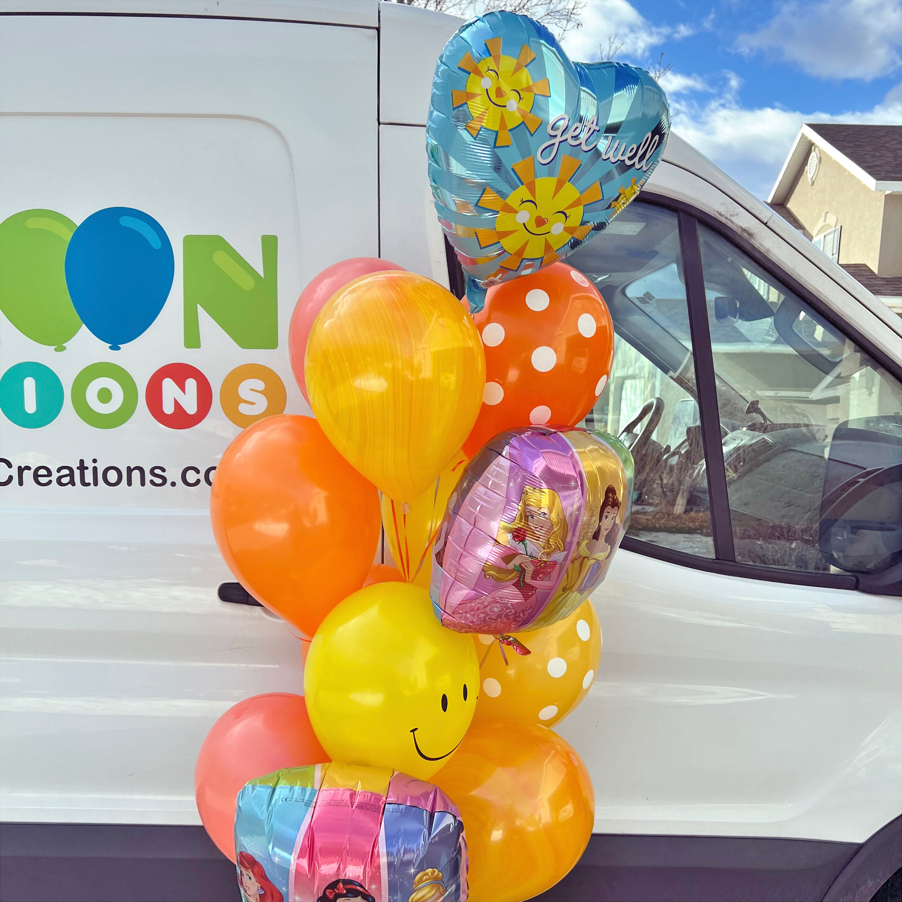 Colorful balloons in front of a vehicle with ' balloon creations' branding.