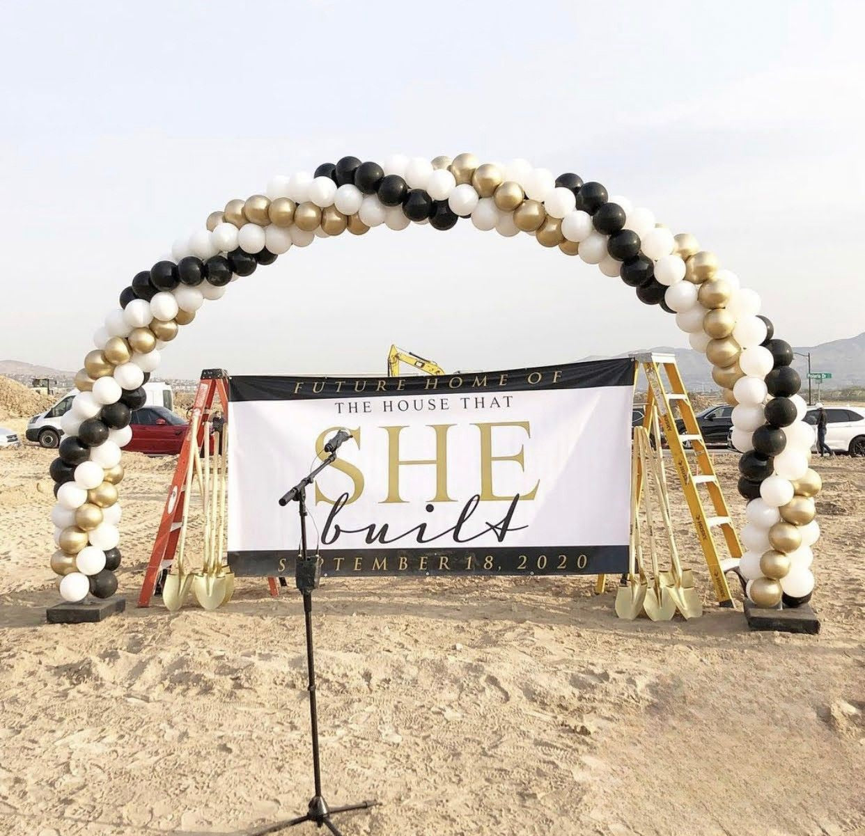 White, black, gold balloon arch stands over build site of upcoming home for groundbreaking event of The House That She Built