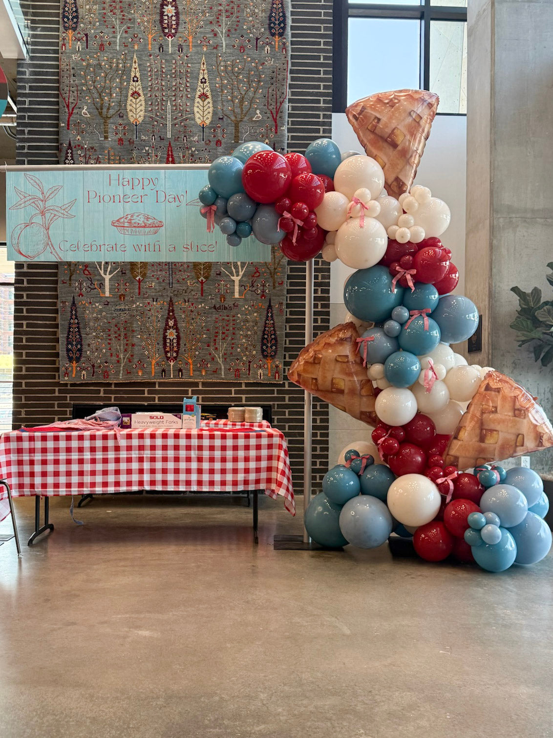 Summer Balloon Garland featuring "Vintage Americana" color scheme with cream, deep red, and blue slate with red gingham ribbon bows. Balloon Garland features apple pie balloon slices incorporated into a "pie" day Pioneer Day in Utah