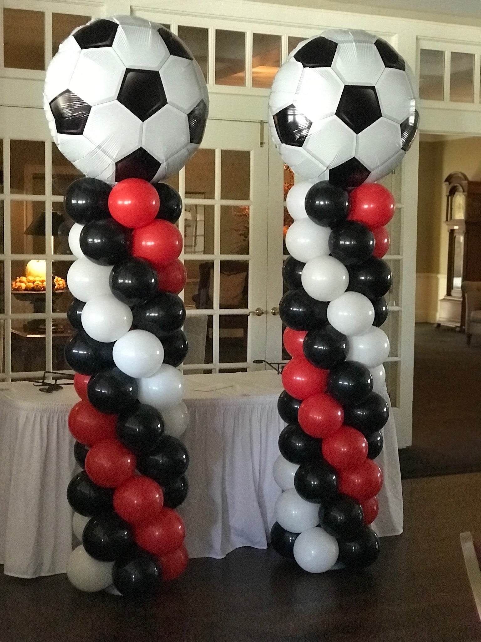Decorative arch made of soccer ball-shaped balloons in black, white, and red at a senior night event.