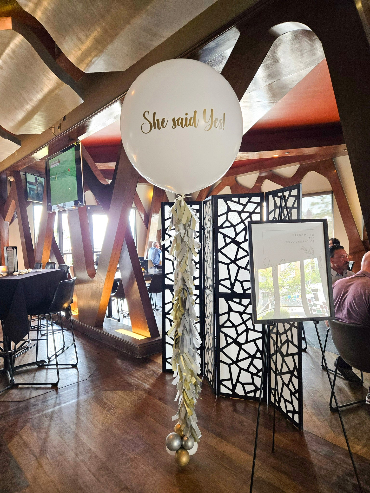 Giant helium balloon reads "She said yes!" in gold with gold and white tissue paper tassel.