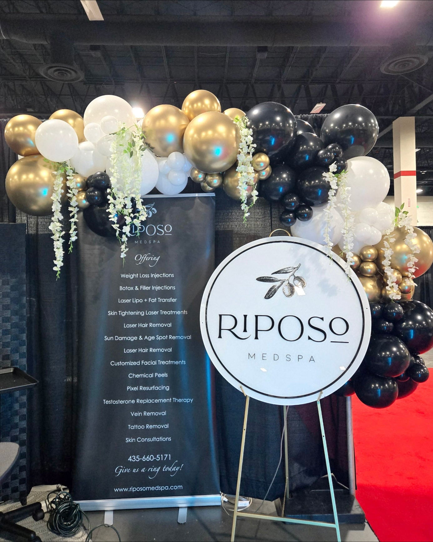 Riposo MedSpa promotional stand with balloon garland and banner at an vendor event - Pinners Conference Utah.