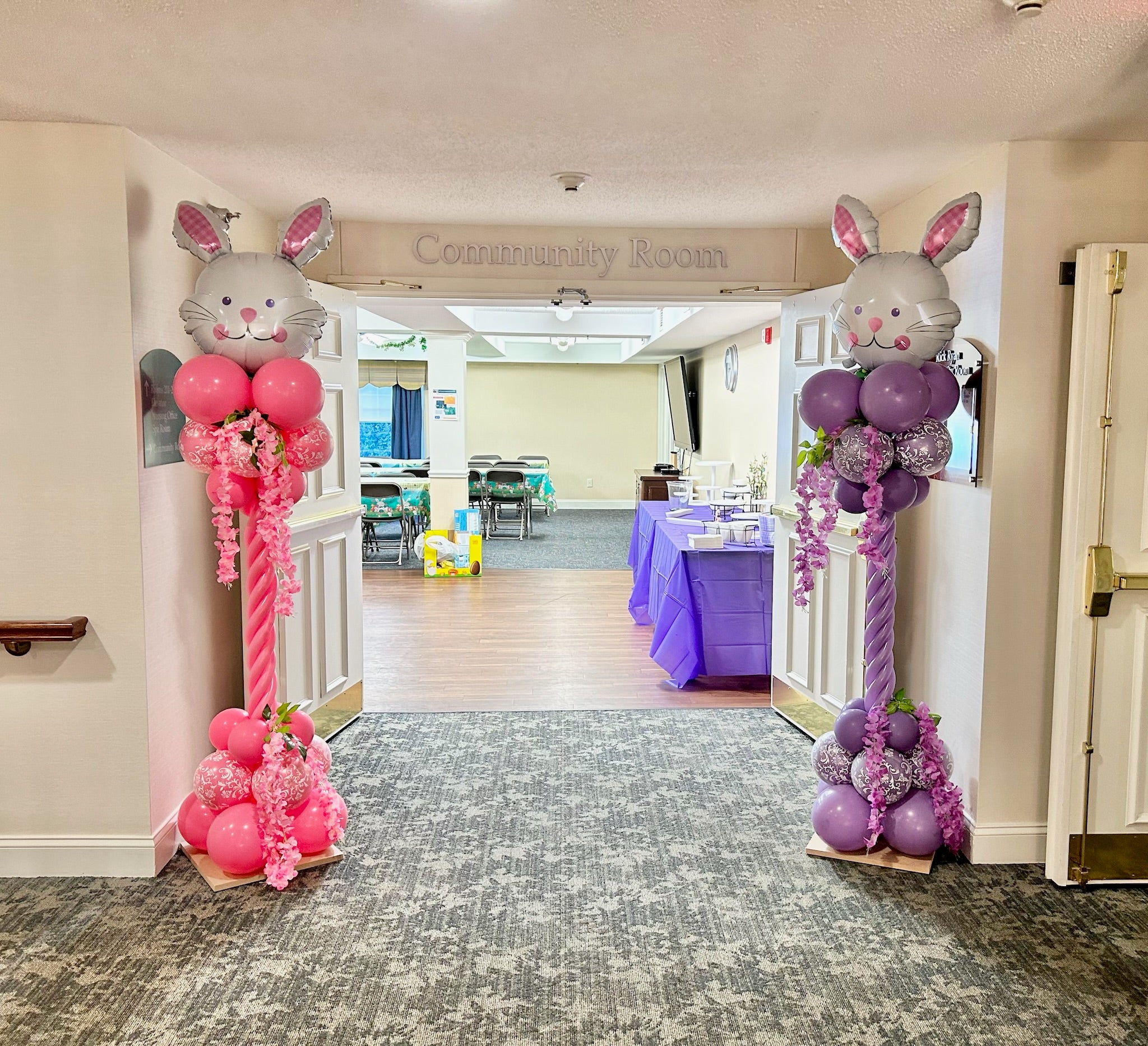 Decorative balloon arches shaped like cartoon characters in a community room.