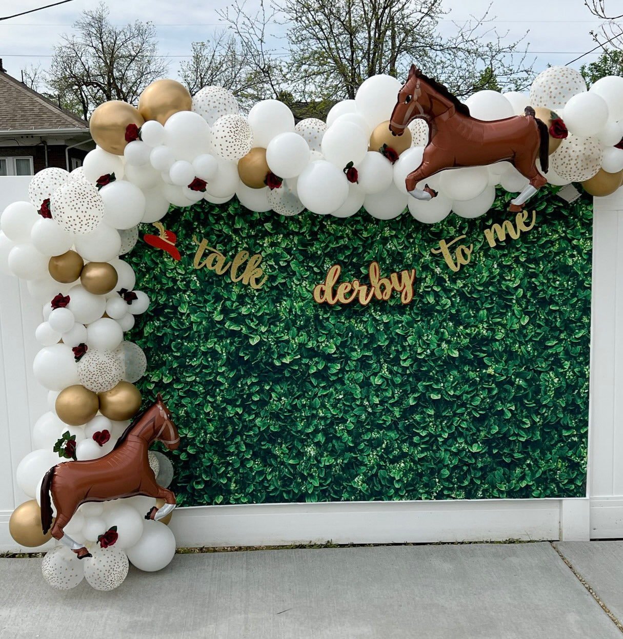 Decorative arch with balloons and horse figures in front of a green hedge with 'talk derby to me' text.